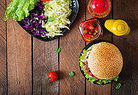 Salat, Burger und verschiedene Saucen aus Vogelperspektive auf Holztisch