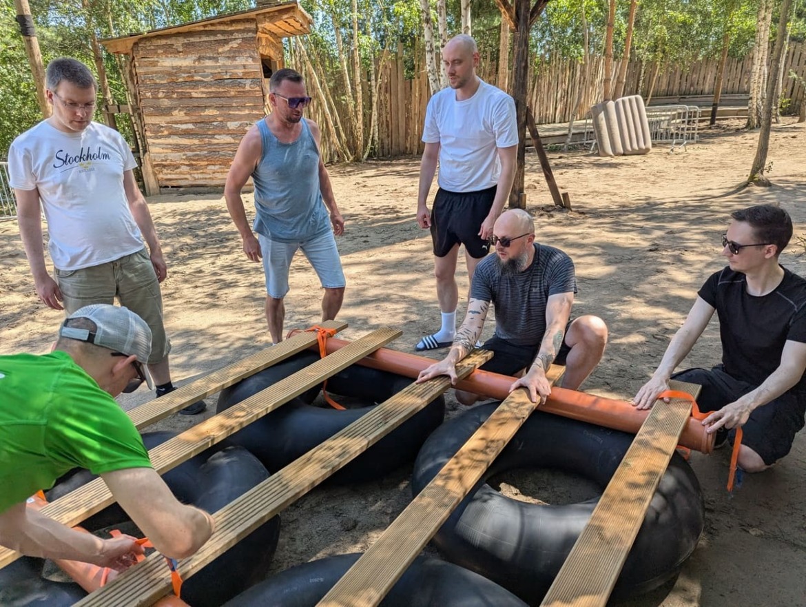 Team 2 bei der Erbauung ihres Floßes, mit Spanngurten werden die Schwimmringe mit den Holzbrettern befestigt