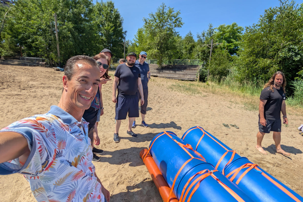 Team 1 macht ein Selfie am Strand, ihr Floß ist auch zu sehen