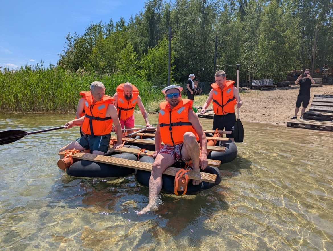 Team 2 besteigt zuversichtlich ihr selbst erbautes Floß aus 4 großen Schwimmringen und Brettern