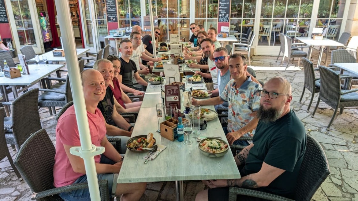 Gruppenfoto vom clickstorm Sommerfest 2026 an langer Tafel mit Speisen und Getränken beim Glashaus Leipzig