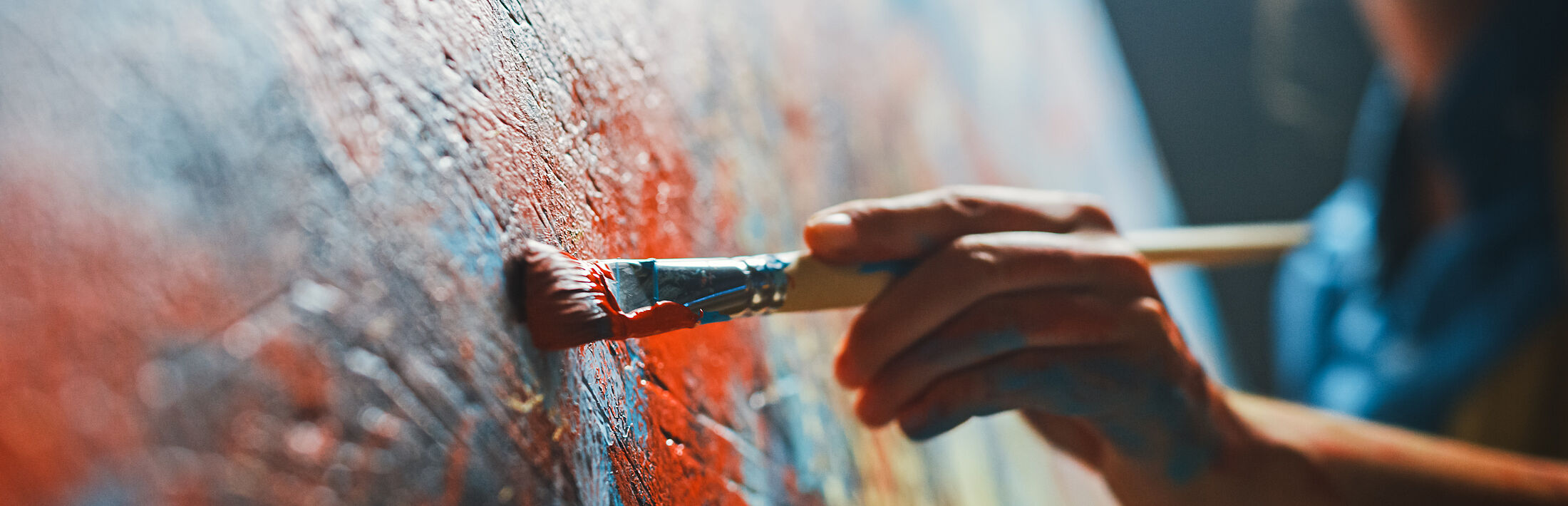 Person malt mit Pinsel Farbe auf große Wand