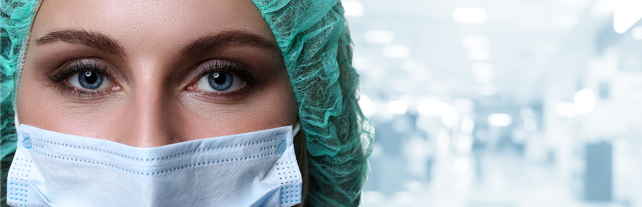 Frau mit Maske und Haarnetz im medizinischen Bereich