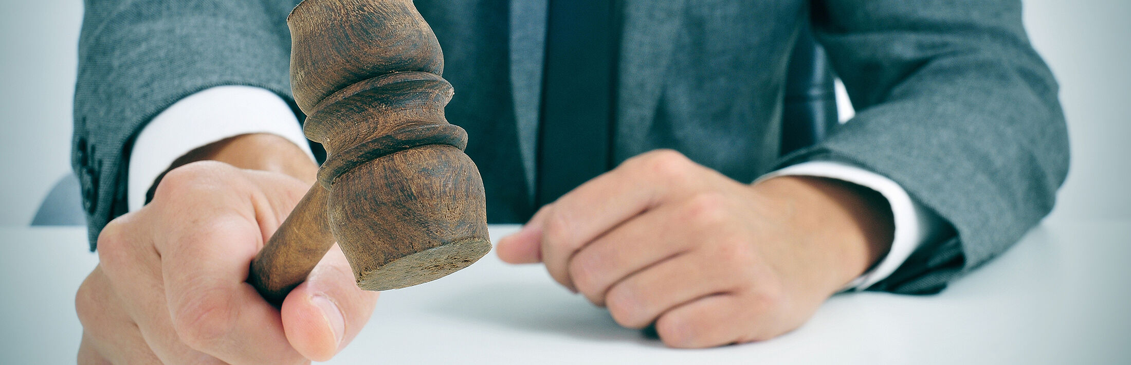 Mann im Anzug mit Auktionshammer in der Hand