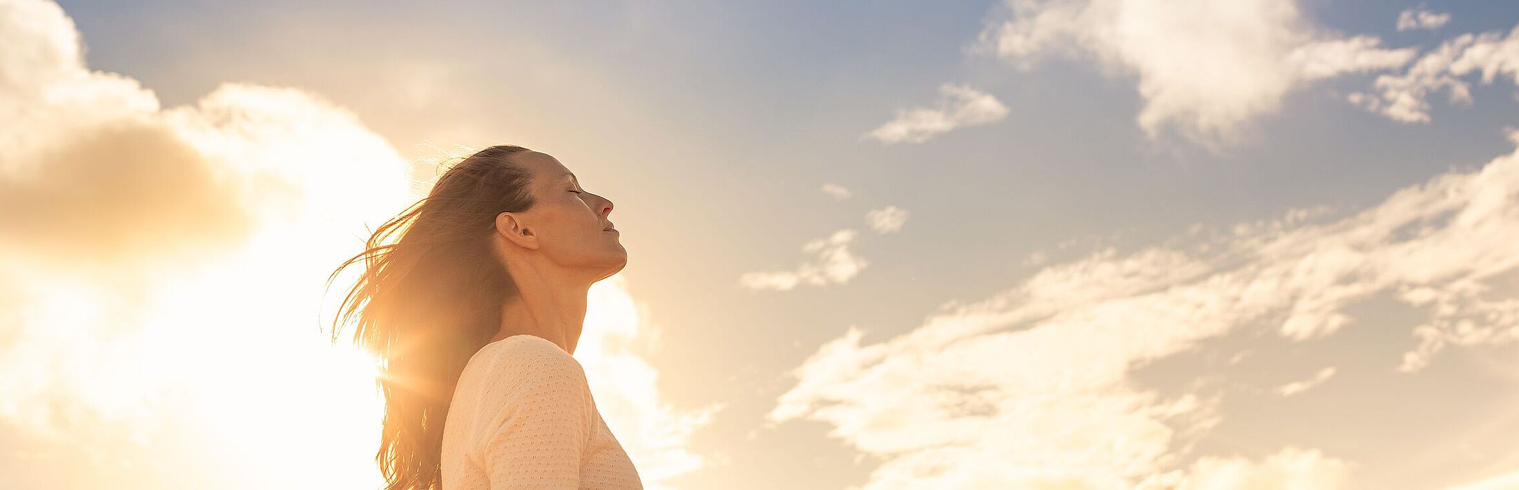 Junge Frau, die mit Gefühlen der Hoffnung und des Glücks zum schönen Himmel hinaufblickt.