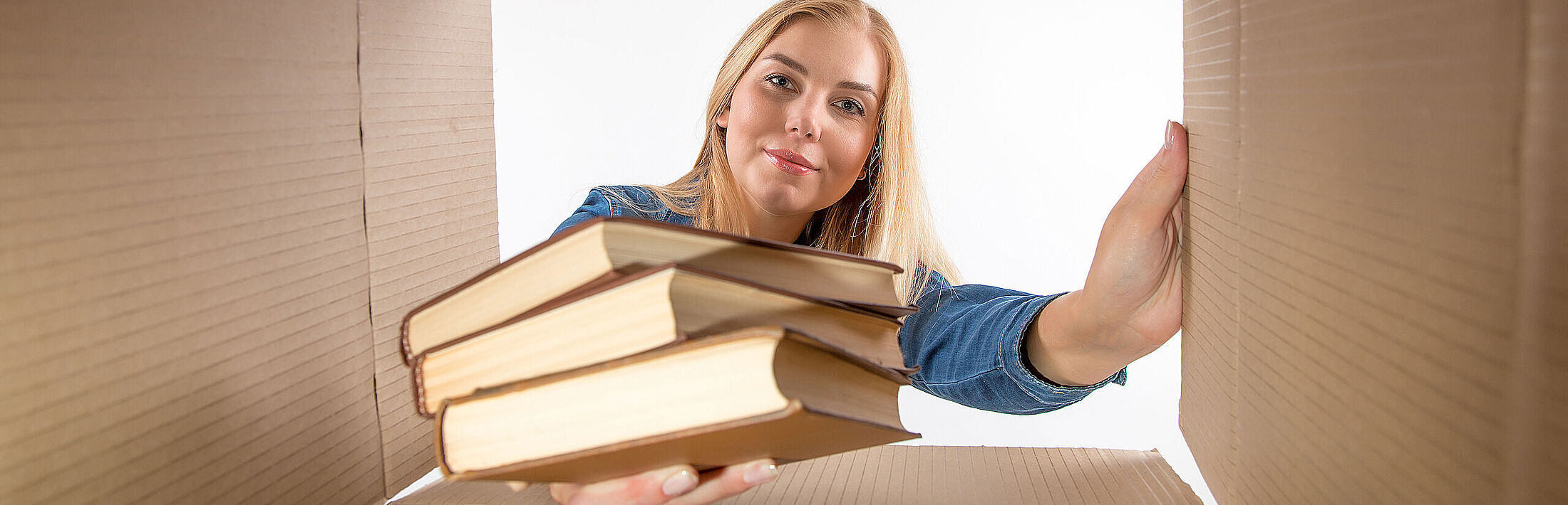 Frau gibt Bücher in Pappkarton