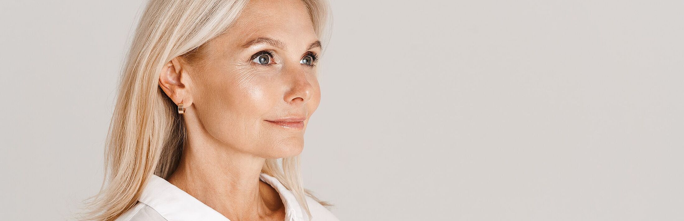 Gesicht einer älteren Dame mit Ohrringen und schulterlangen blonden Haar im Seitenprofil