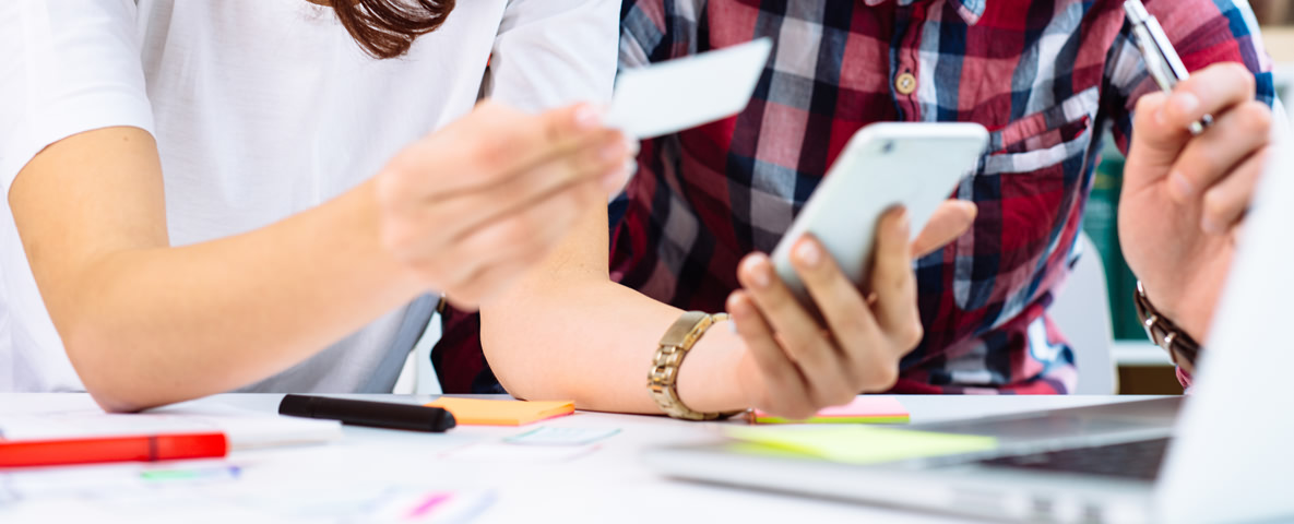 2 Personen mit Smartphone und Visitenkarte vor Labtop