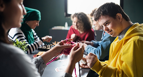 Gruppe von Menschen, die Karten und Brettspiele im Gemeindezentrum spielen, Inklusivität von Behinderten.