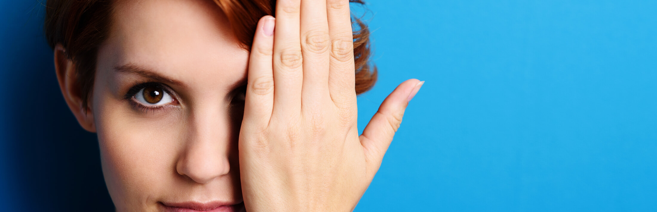 Frau mit einer Hand vor dem linken Auge